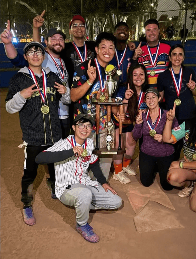 Group of friends in sports jerseys cheering at a bar after a game, pints raised